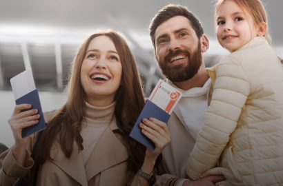 Happy Family Holding Passports and Boarding Passes at the Airport A happy family, consisting of a woman, a man, and a young girl, is at the airport. The parents are holding passports and boarding passes, ready for their trip.